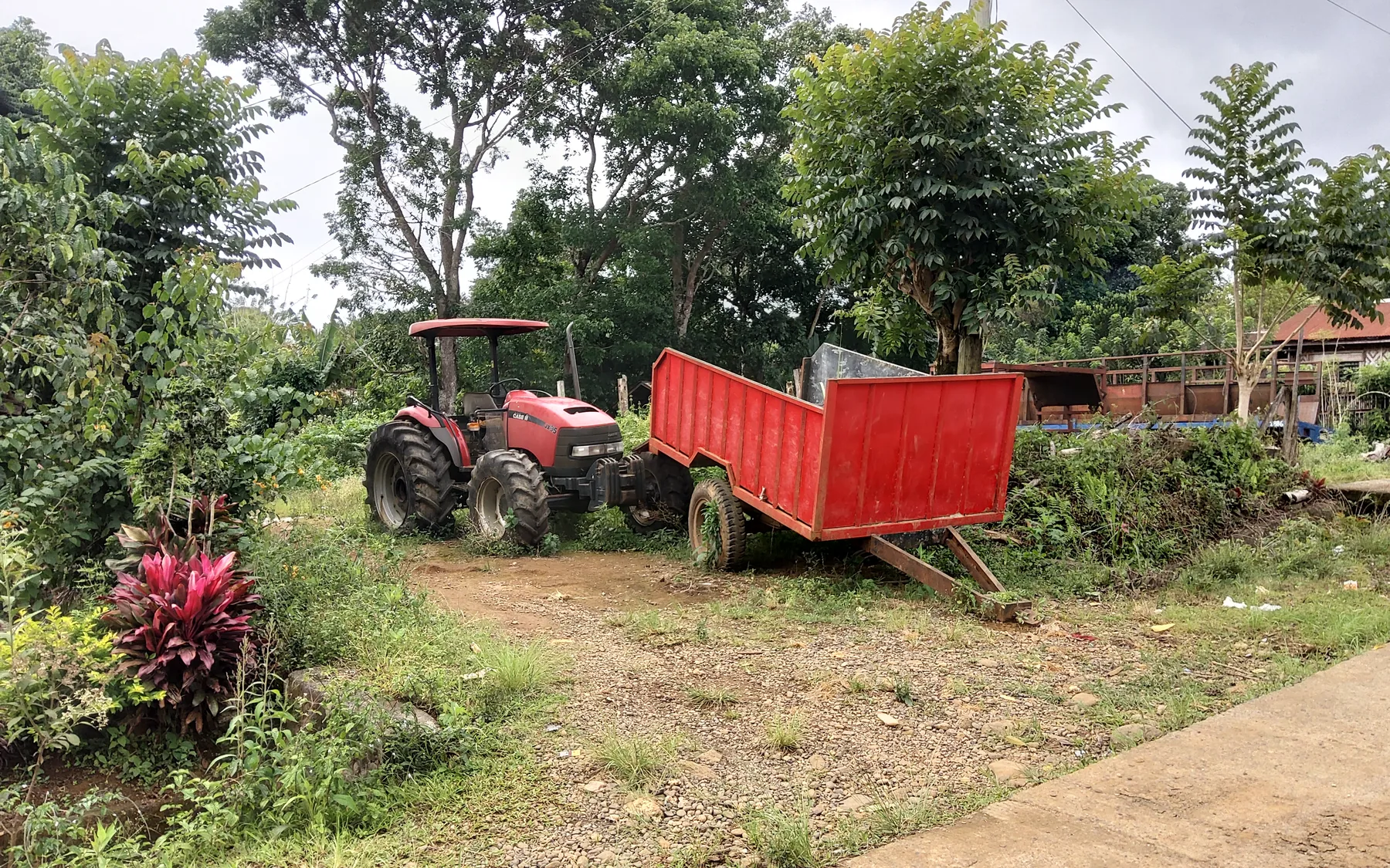 BMMPC tractor and red hauling trailer surrounded by vegetation